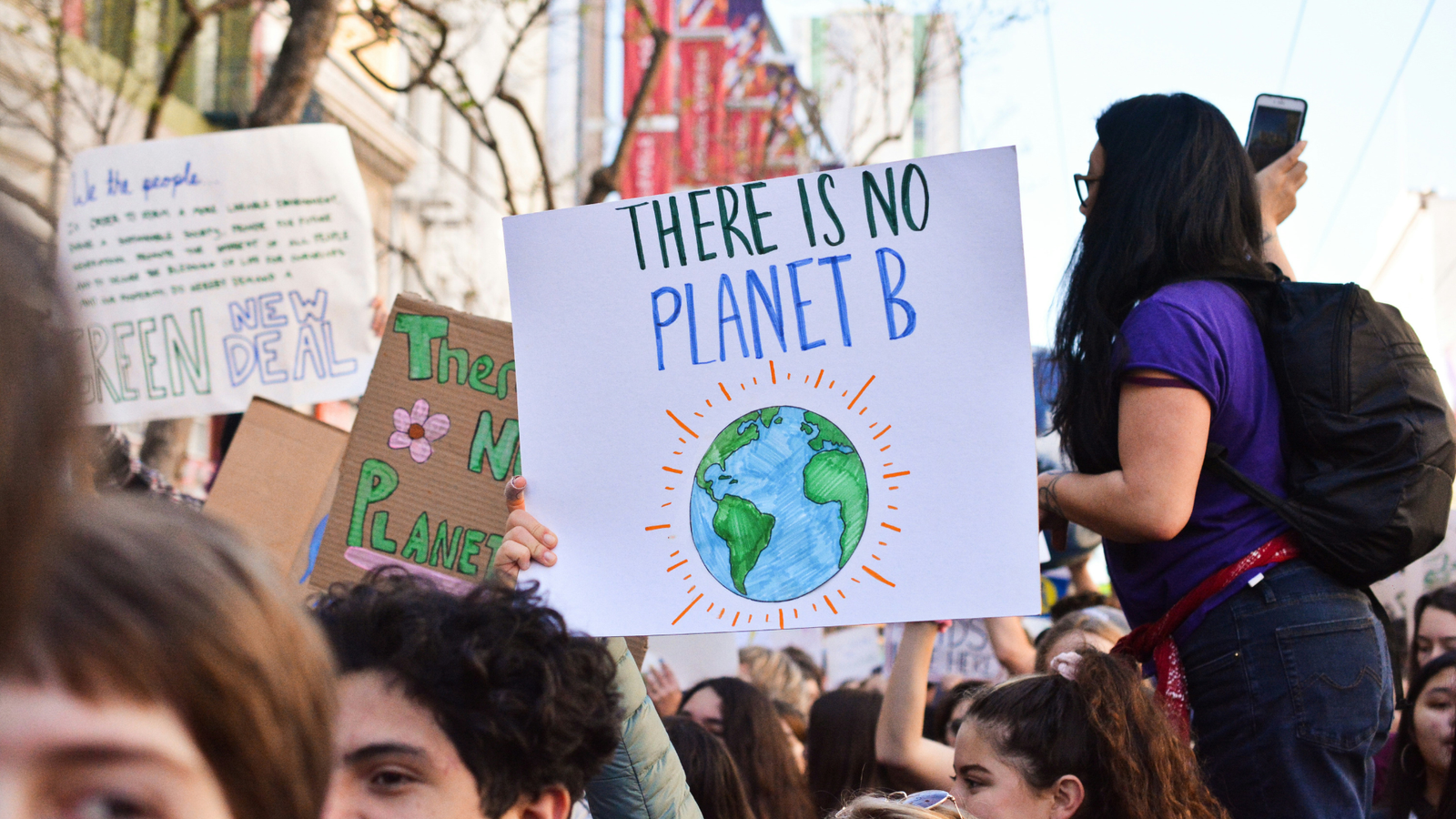 A march for the planet. A person holds aloft a sign that says 'There is no Planet B.'